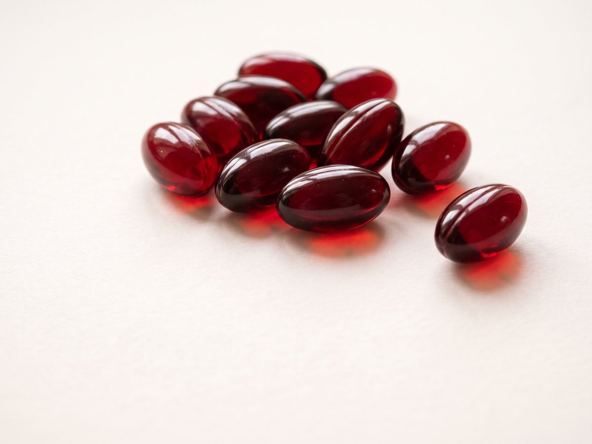 A loose cluster of ruby-red softgels on a clean white surface